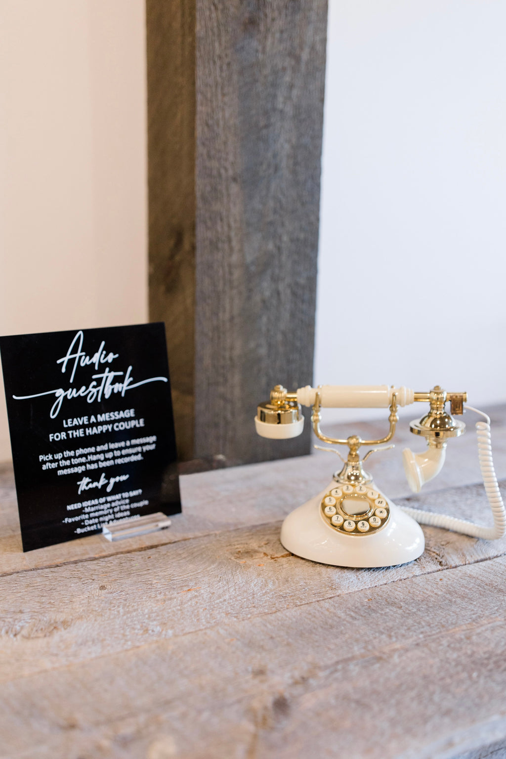 Vintage-style white and gold phone on a wooden surface with a black card next to it.