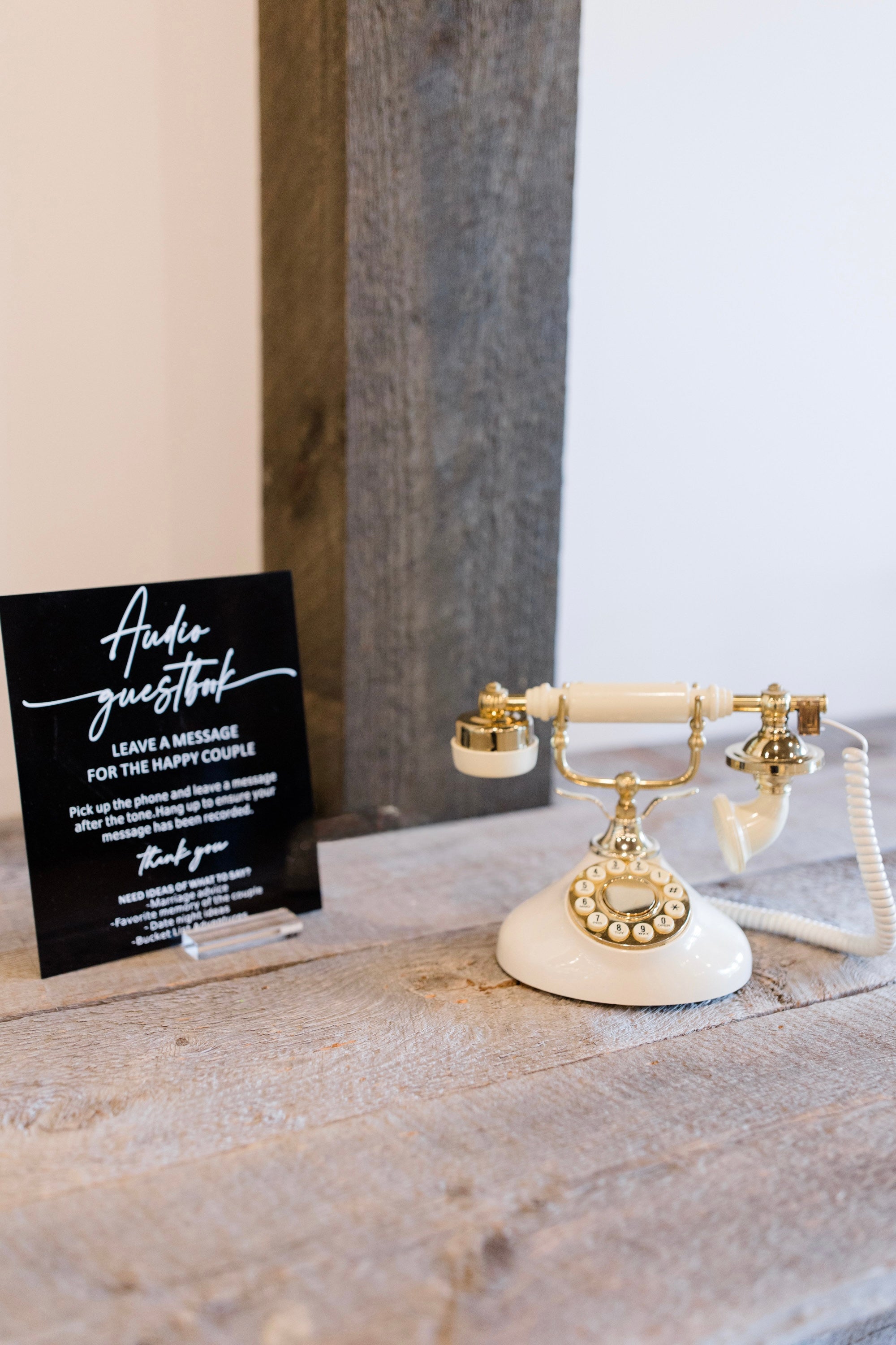 Vintage-style white and gold phone on a wooden surface with a black card next to it.