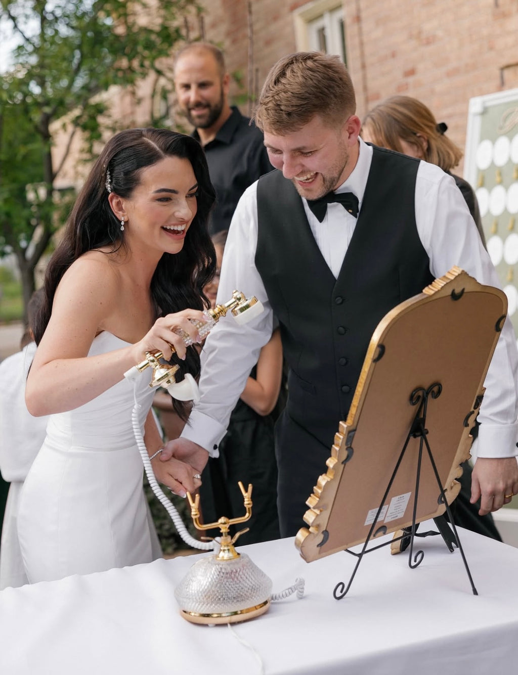 Man and woman in formal attire interacting with a decorative object outdoors.